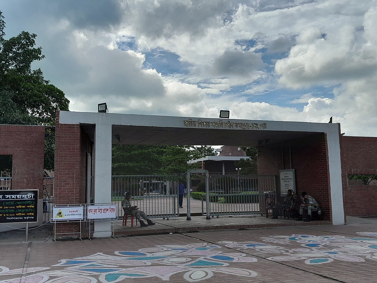 বঙ্গবন্ধু সমাধিসৌধ কমপ্লেক্সের প্রবেশদ্বার — লাল ইট ও সাদা কংক্রিটের সমন্বয়, পাঠযোগ্য বাংলা লেখা। সূত্র: উইকিমিডিয়া কমন্স